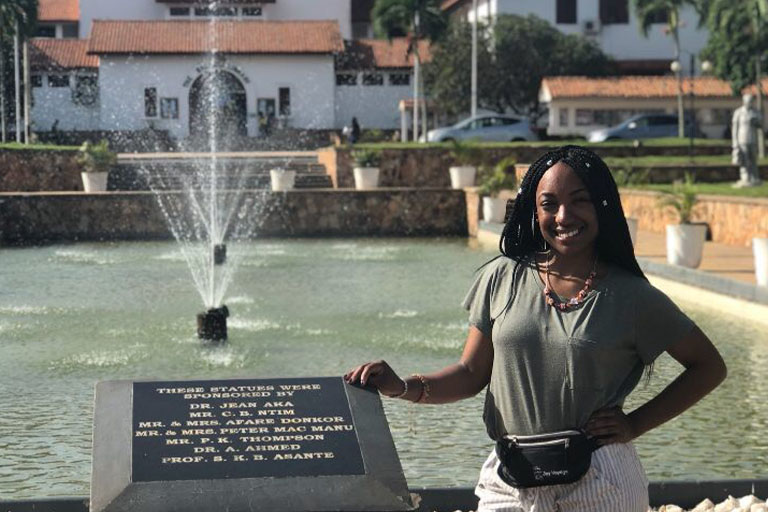 Shayauna Brewer poses in front of plaque before a water fountain feature